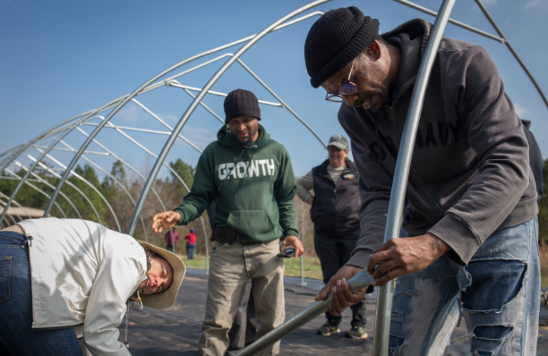 Volunteers work together to build a high-tunnel during an educational farmer-brigade event at Fairpoint Farms in Kittrell, NC on February 27, 2023.